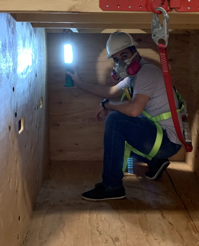 A trainee in a harness and respirator inside the confined space mock-up