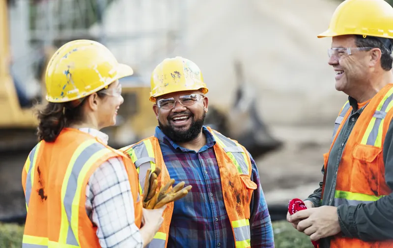 Construction workers in hard hats and vests talking on site