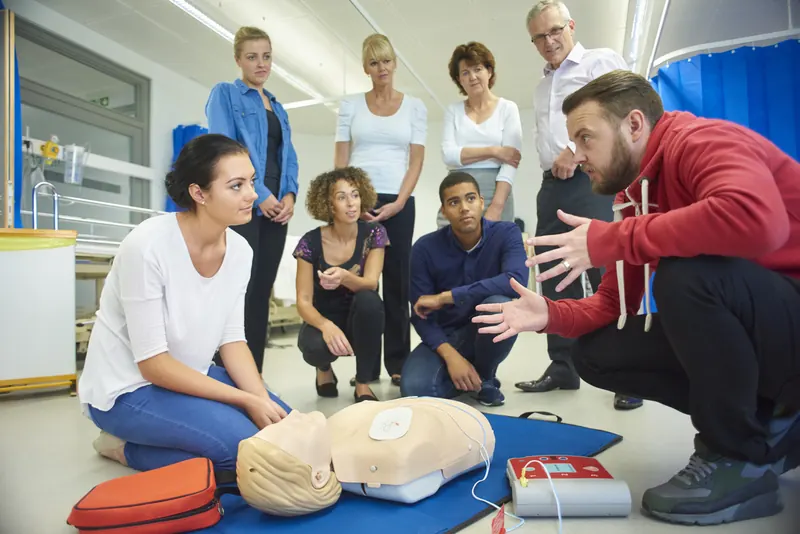 A first aid class practising CPR on mannequins