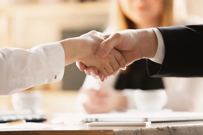 Two people shaking hands across a table