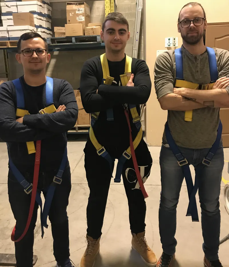Three trainees in fall arrest harnesses after Working at Heights training at the Concord centre