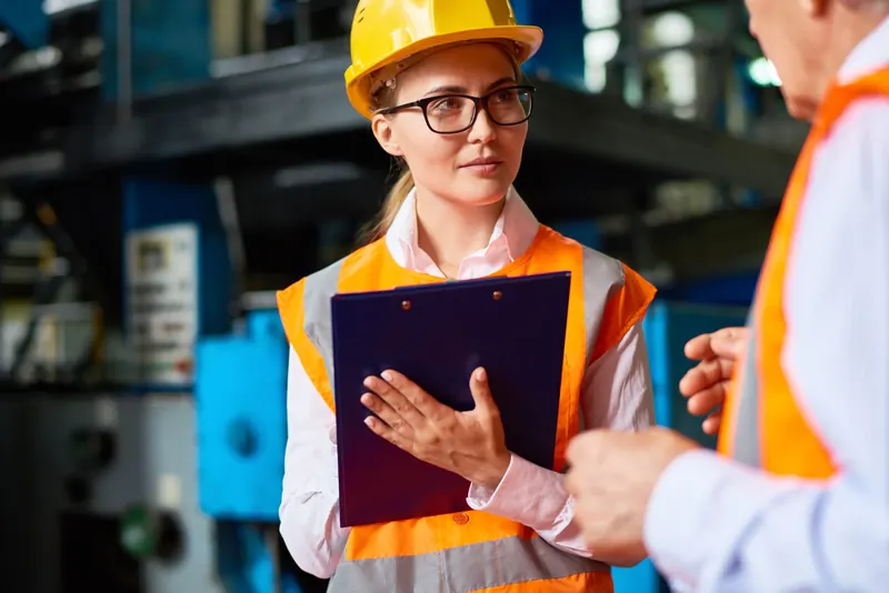 A health and safety auditor with a clipboard on a plant floor