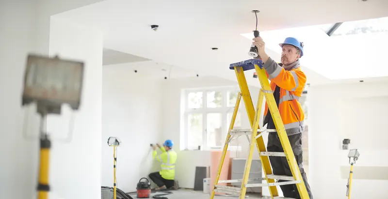 A worker in a vest on a stepladder