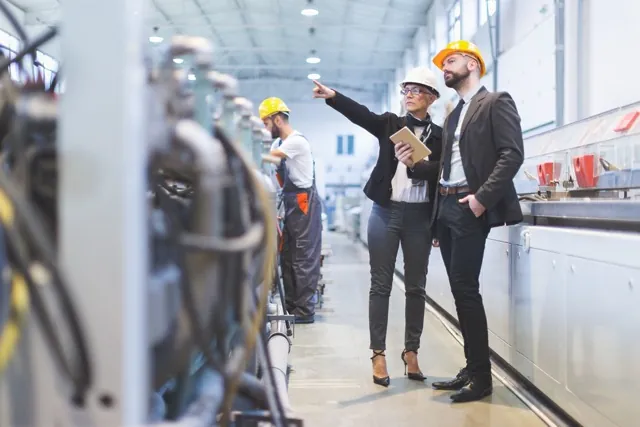 Managers in hard hats walking through a plant