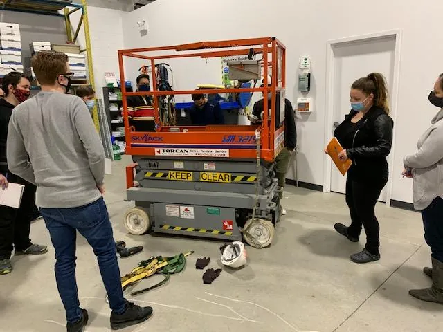 Trainees gathered around a scissor lift during practical training