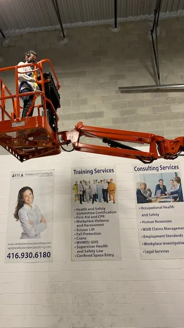 A boom lift in front of the training and consulting services wall