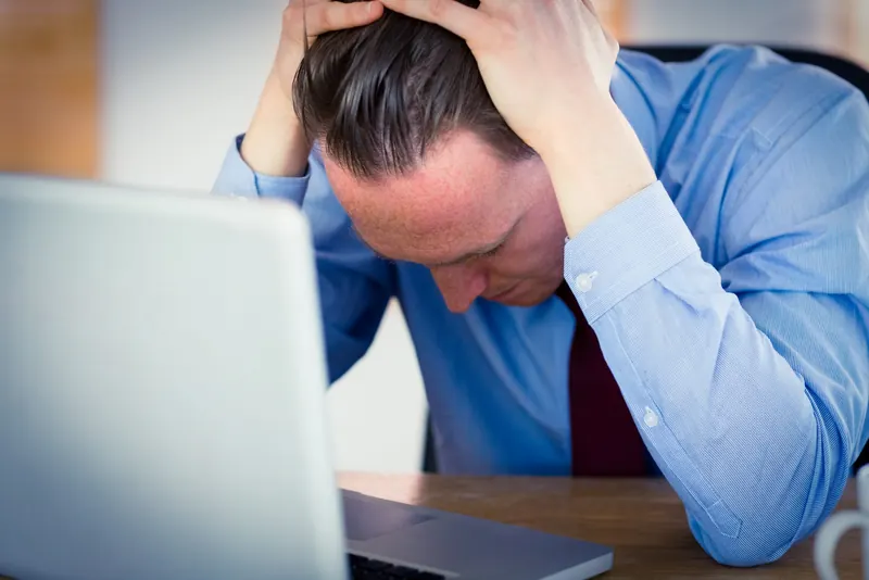 A stressed employee with his head in his hands